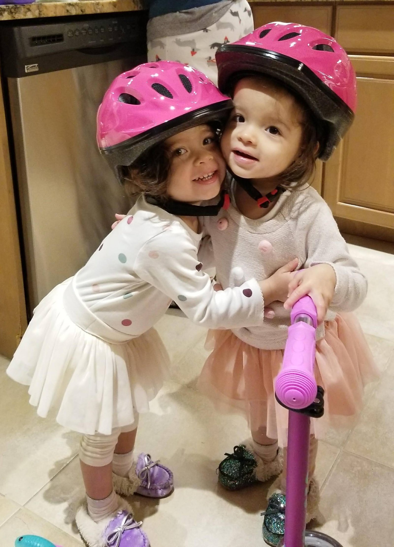 Charlie and JoJo in pink bike helmets hugging in 2019