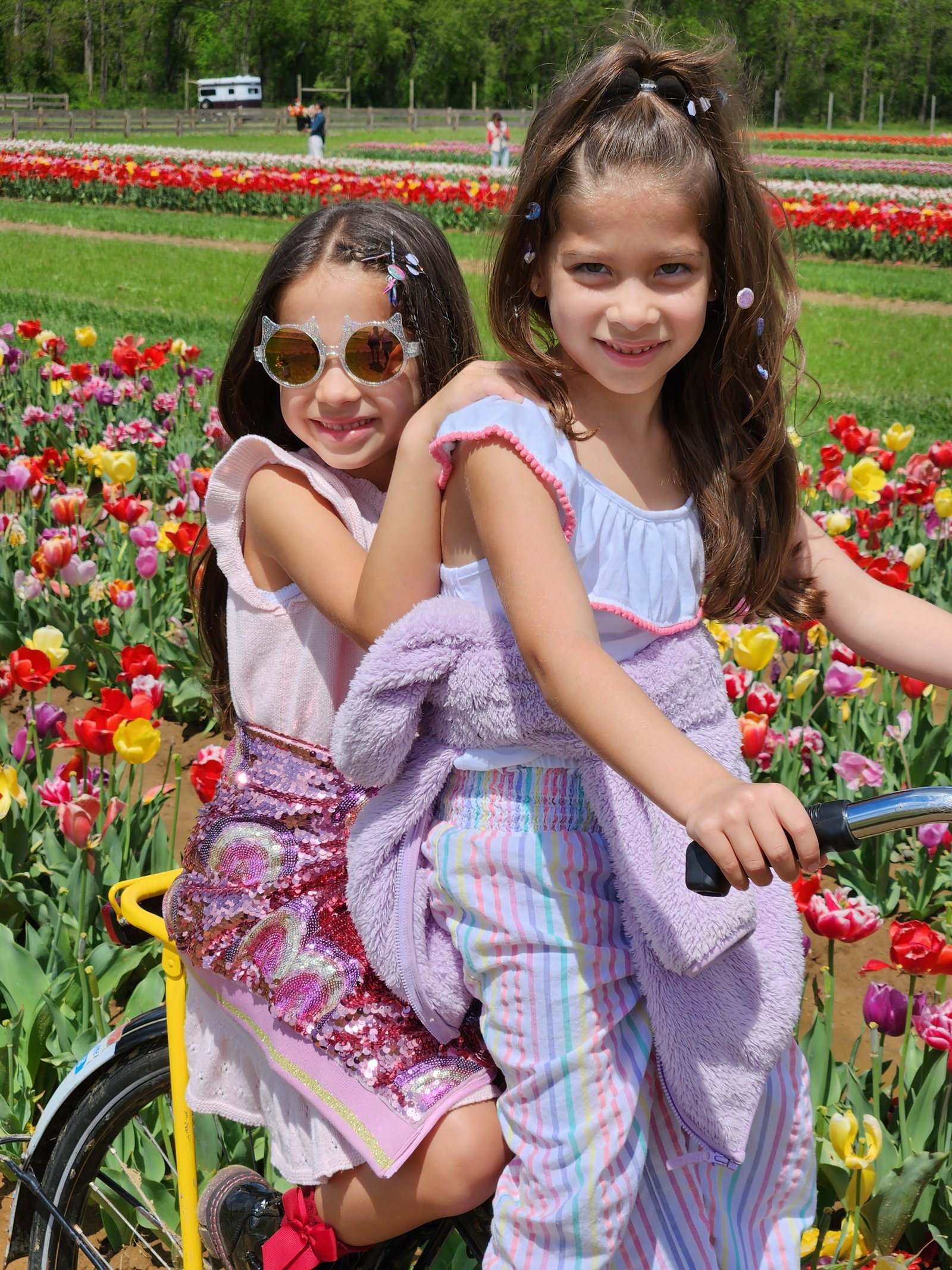 Charlie and JoJo hugging on a bicycle in a tulip field in 2023