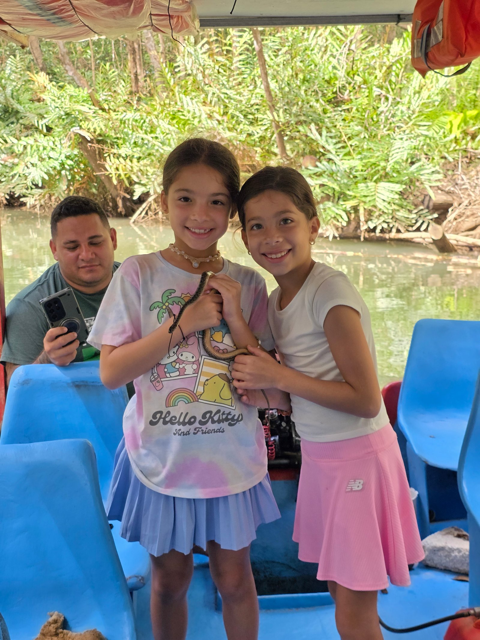 Both girls holding snake on jungle boat cruise in Costa Rica