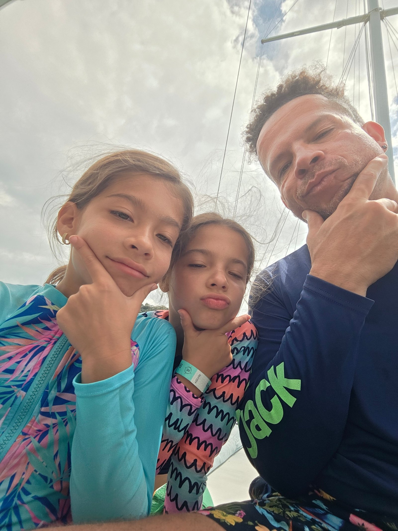 Bobby and twin girls chin-on-hand pose on sailboat in Costa Rica