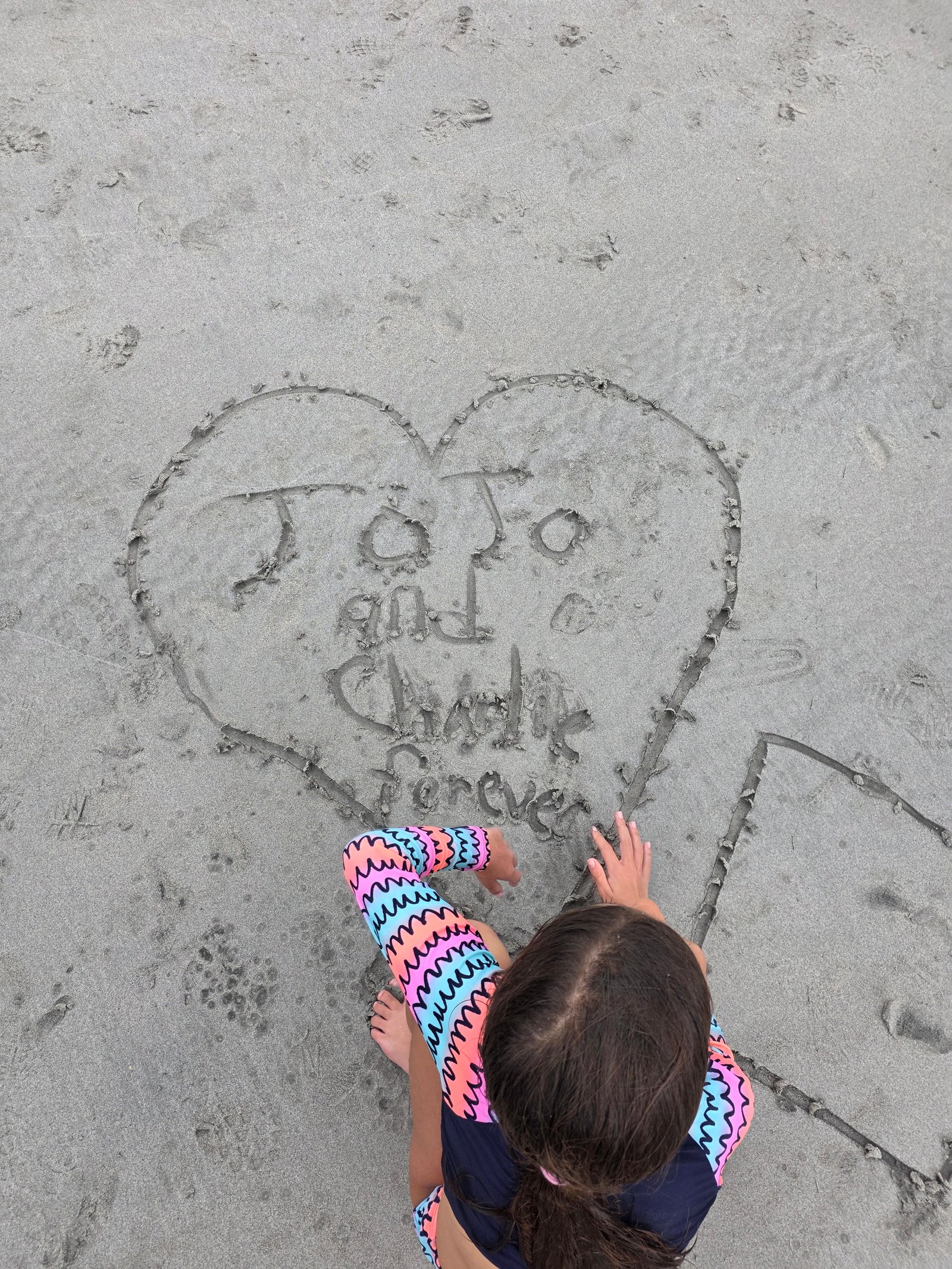 JoJo writing JoJo and Charlie Forever heart in sand