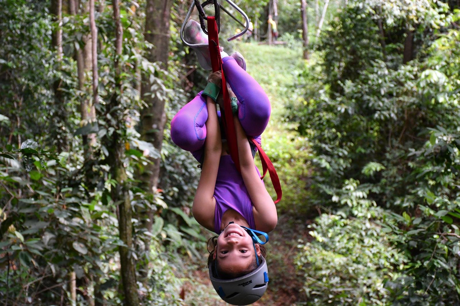 JoJo zip lining upside down through jungle