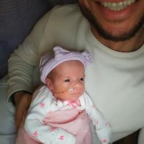 Bobby holding one of his daughters in a pink outfit in the NICU